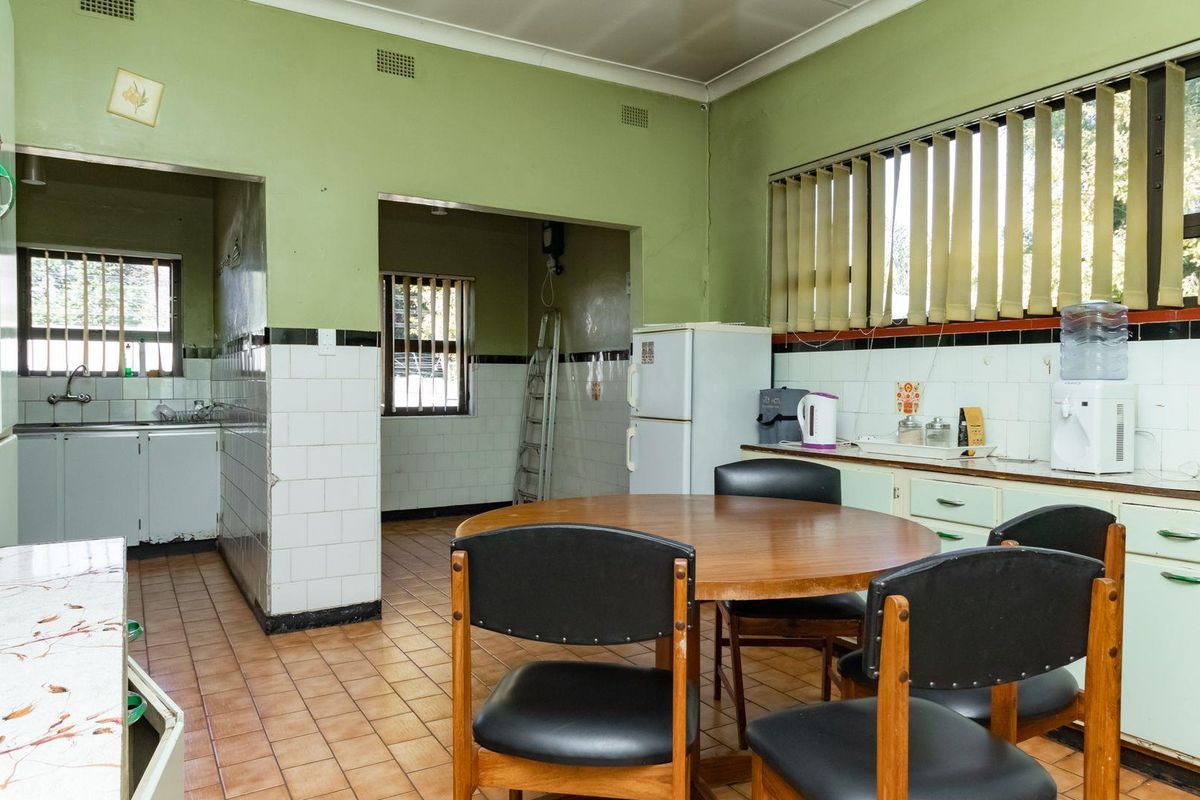 A dated kitchen and dining area featuring original cabinetry, tiled walls, and ceramic floor tiles, offering significant potential for a modern renovation.