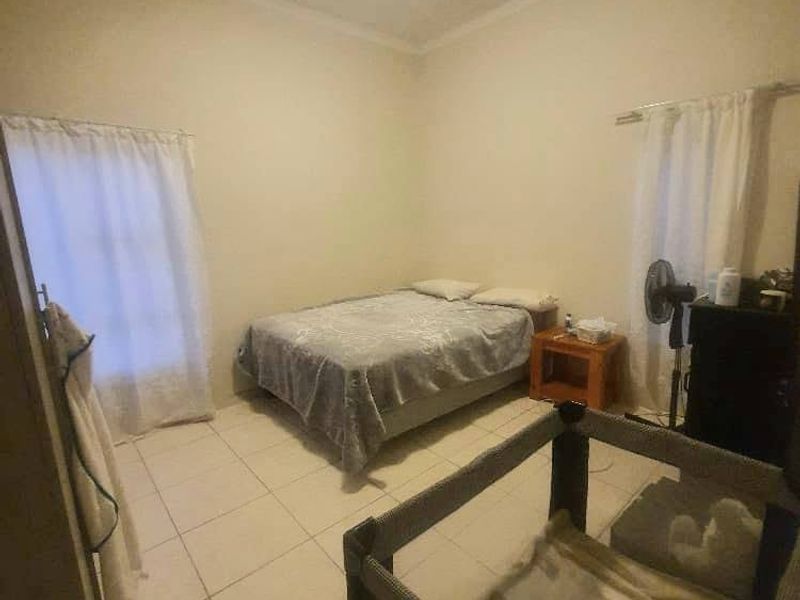 A functional bedroom featuring tiled flooring and neutral wall finishes, providing a simple and practical living space.