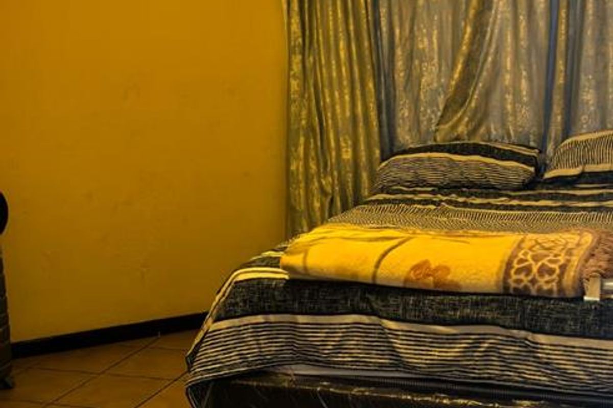 A bedroom featuring tiled flooring and yellow painted walls, requiring cosmetic updates to improve the overall aesthetic and finish.
