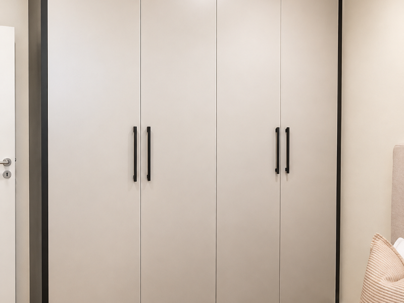 A modern bedroom featuring a large, sleek built-in wardrobe with contrasting dark trim and minimalist handles, providing ample storage space.