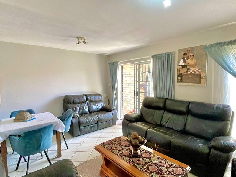 A living room featuring tiled flooring and a sliding glass door with an integrated security gate, providing access to the exterior.