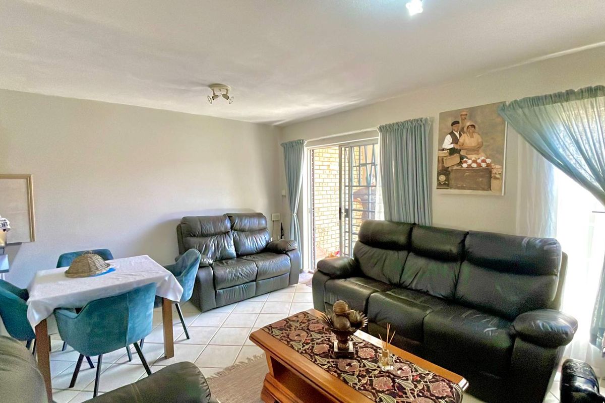 A living room featuring tiled flooring and a sliding glass door with an integrated security gate, providing access to the exterior.