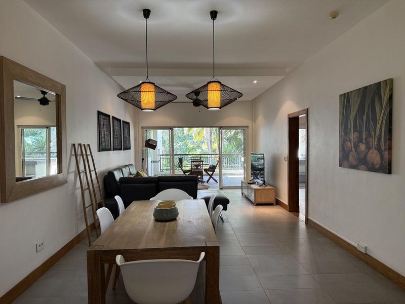 Spacious open-plan living and dining area featuring tiled floors, modern pendant lighting, and large sliding glass doors leading to an outdoor balcony.