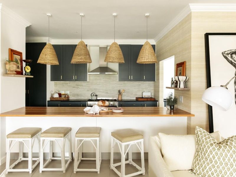 Modern open-plan kitchen featuring dark cabinetry, a timber breakfast bar, and integrated appliances, seamlessly connecting to the living area.