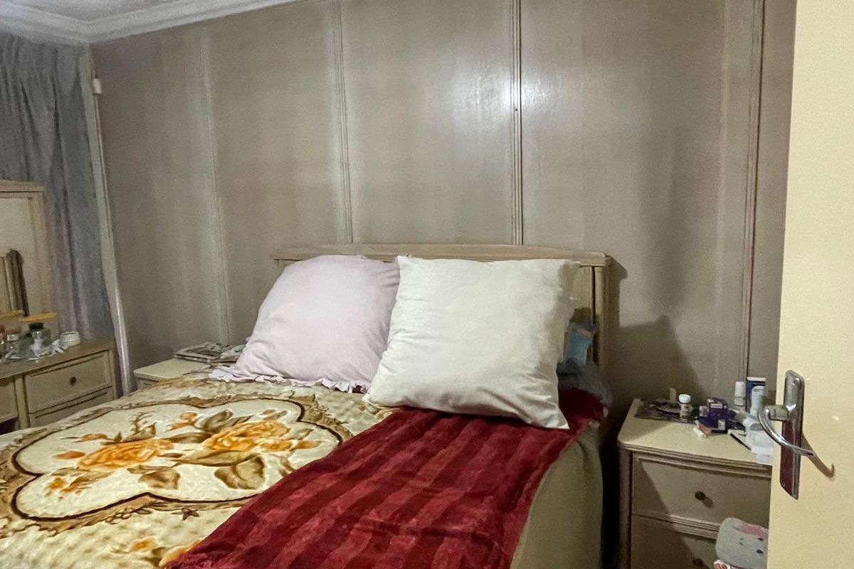 A bedroom featuring panelled walls and decorative coving, currently presenting with dated finishes that could benefit from a modern update.