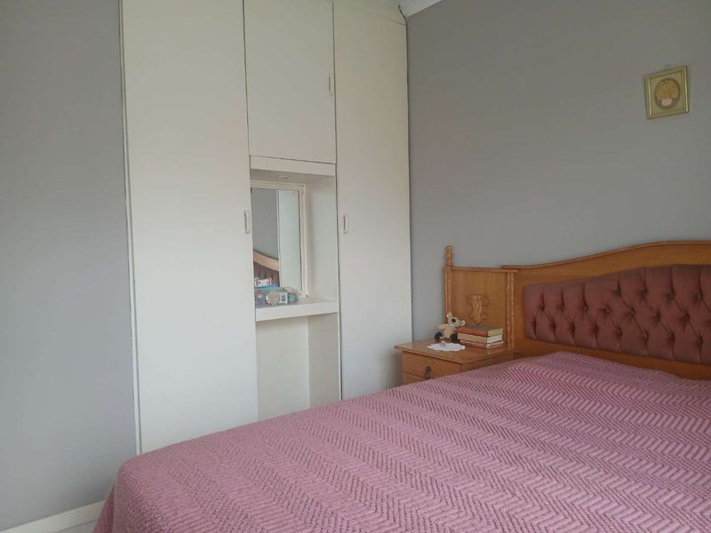 A bedroom featuring a floor-to-ceiling built-in wardrobe with an integrated vanity mirror section.