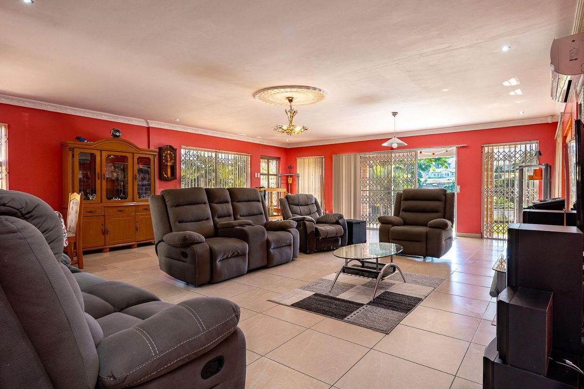 Spacious living room featuring tiled flooring, decorative ceiling rose, and sliding glass doors leading to an outdoor area.
