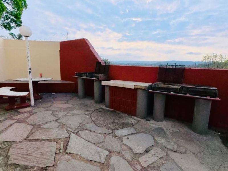 Outdoor patio area featuring built-in barbecue stations, stone flooring, and perimeter walls with elevated views.