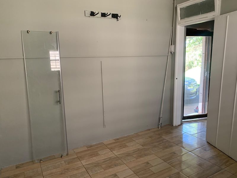 An empty entry area featuring tiled flooring, wall-mounted hooks, and direct access to the exterior through a glass-paneled door.