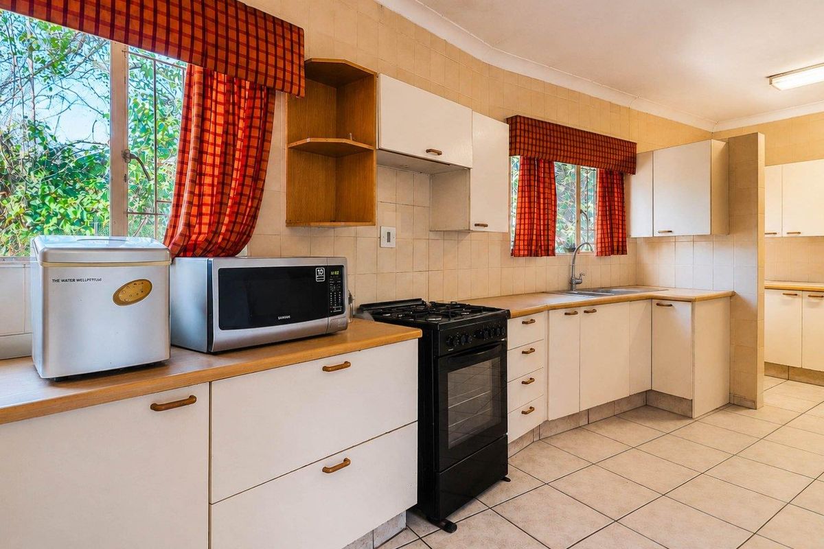 A functional kitchen featuring white cabinetry, laminate countertops, a gas stove, and tiled flooring, offering a practical layout with ample natural light.
