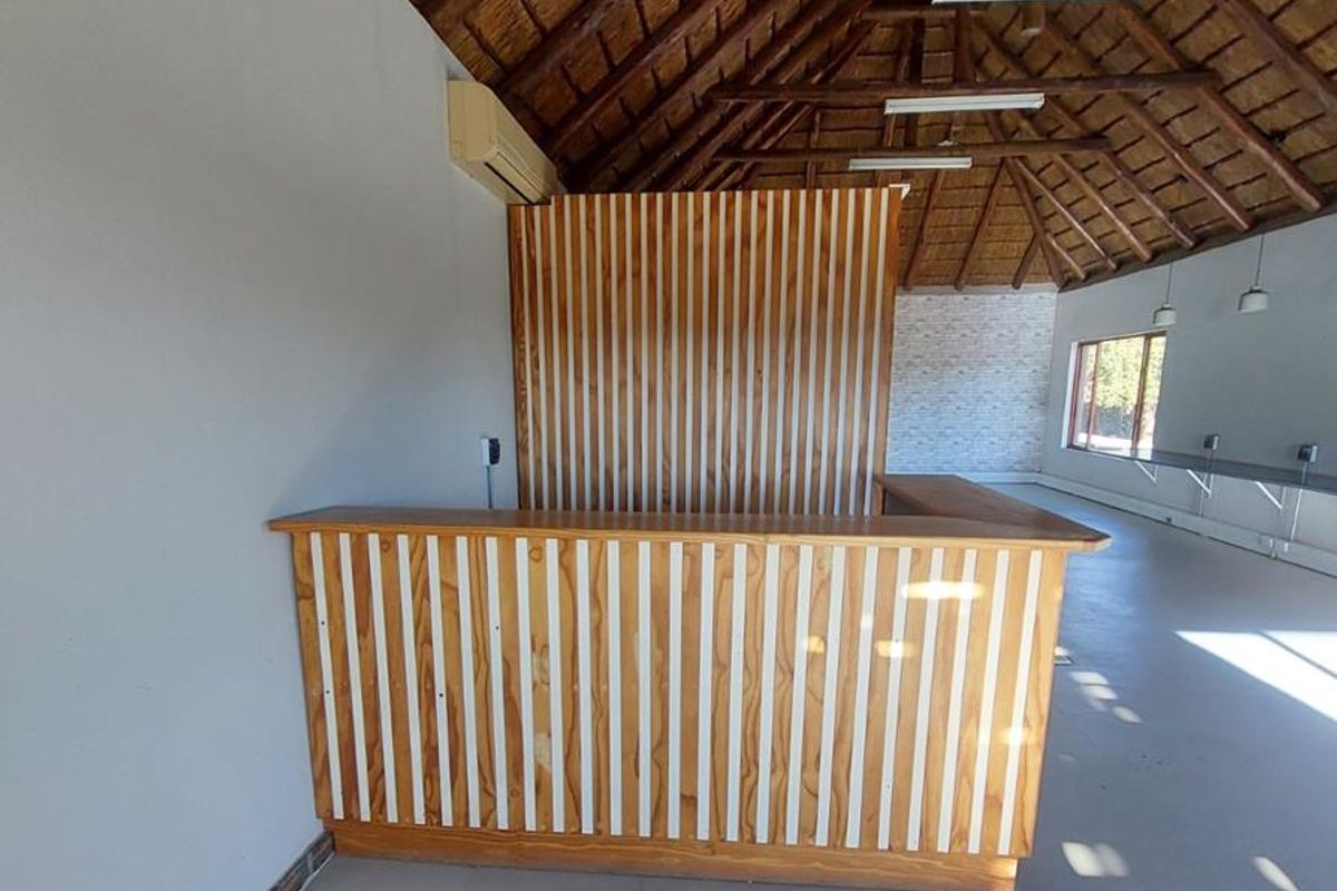 Spacious office area featuring a high vaulted thatched roof, exposed timber beams, and a built-in wooden reception counter.