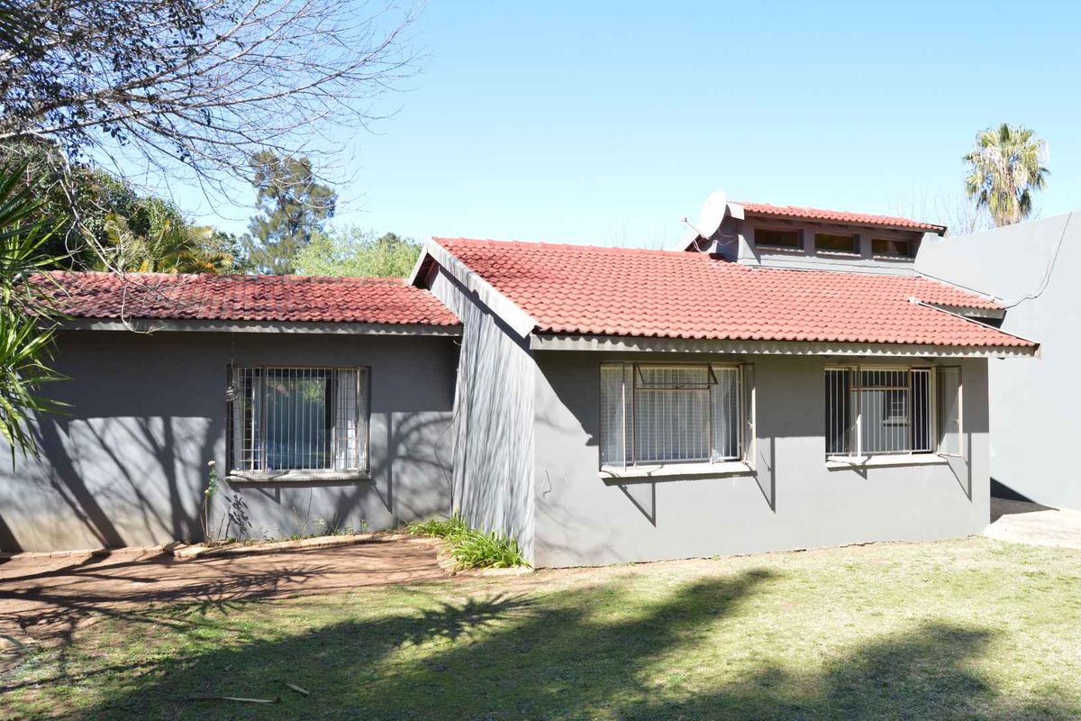 Rear view of a single-story house featuring a terracotta tiled roof, grey painted exterior walls, and security bars on the windows.