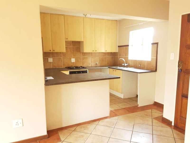 A functional kitchen featuring built-in cabinetry, laminate countertops, a tiled backsplash, and integrated cooking appliances with tiled flooring throughout.