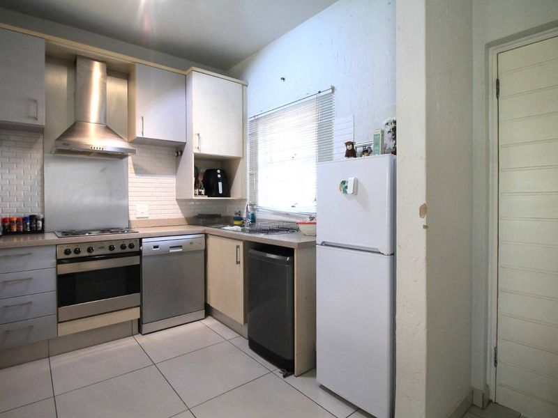 A functional kitchen featuring built-in cabinetry, a stainless steel oven and extractor fan, subway tile backsplash, and tiled flooring.