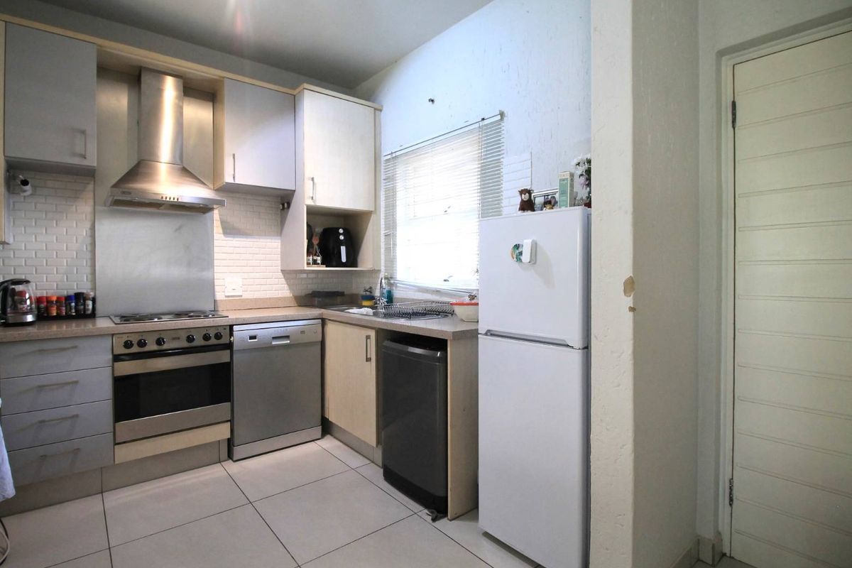 A functional kitchen featuring built-in cabinetry, a stainless steel oven and extractor fan, subway tile backsplash, and tiled flooring.