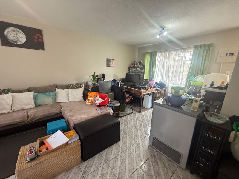 Open plan living area featuring tiled flooring and access to a patio through a security gate.