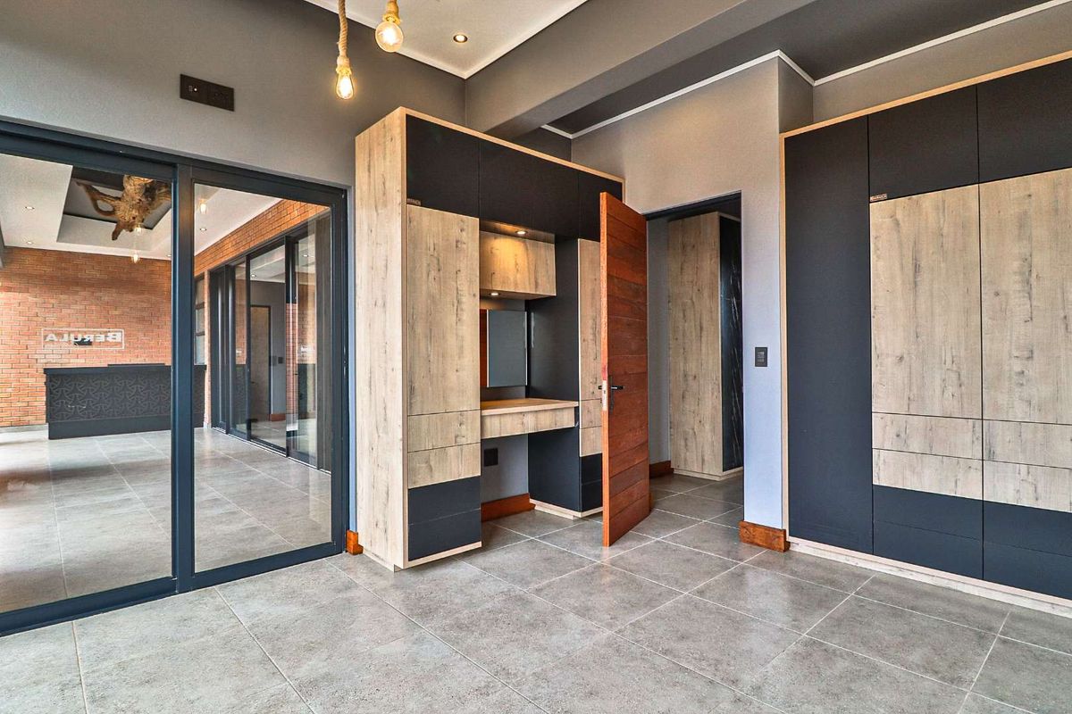 Modern interior space featuring built-in cabinetry with a integrated vanity desk, tiled flooring, and glass sliding doors leading to an adjacent room.