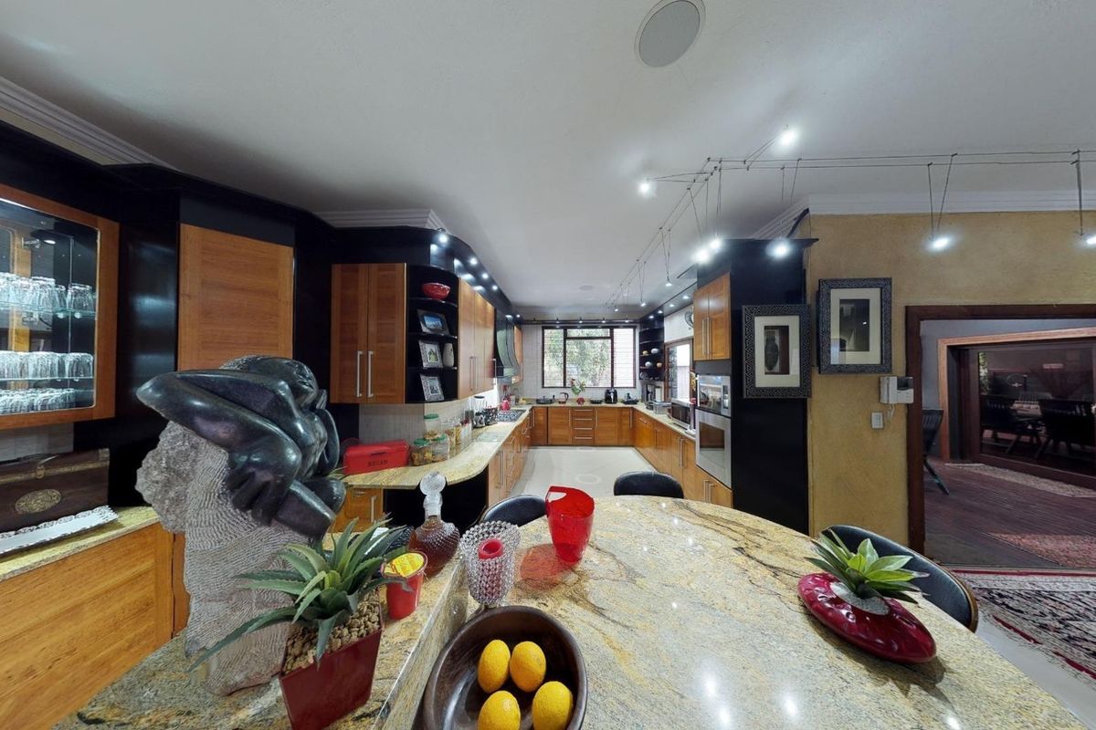 Spacious kitchen featuring extensive wooden cabinetry, granite countertops, built-in appliances, and integrated lighting, offering a functional and well-organized culinary workspace.