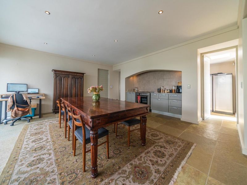 Open-plan dining area featuring tiled floors, recessed lighting, and a recessed kitchen nook with built-in cabinetry and integrated cooking appliances.