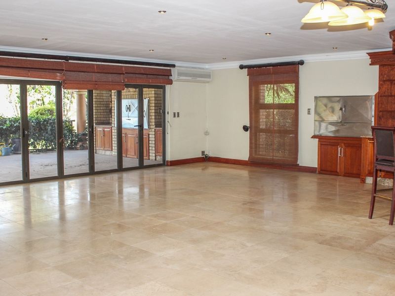Spacious living area featuring stone tile flooring, a built-in bar, and large sliding doors providing seamless access to the outdoor patio.