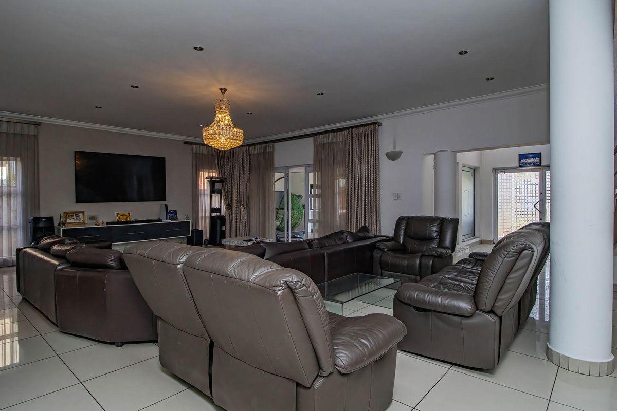 Spacious living room featuring large format floor tiles, recessed downlighting, and a prominent structural column, with direct access to the outdoor area.