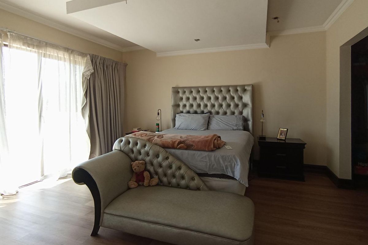 Spacious bedroom featuring wood-look flooring, a recessed ceiling detail, and sliding glass doors providing access to the exterior.