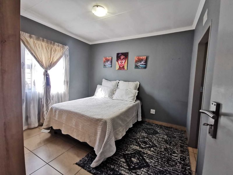 A well-maintained bedroom featuring neutral grey walls, tiled flooring, and a ceiling-mounted light fixture, offering a comfortable and functional living space.
