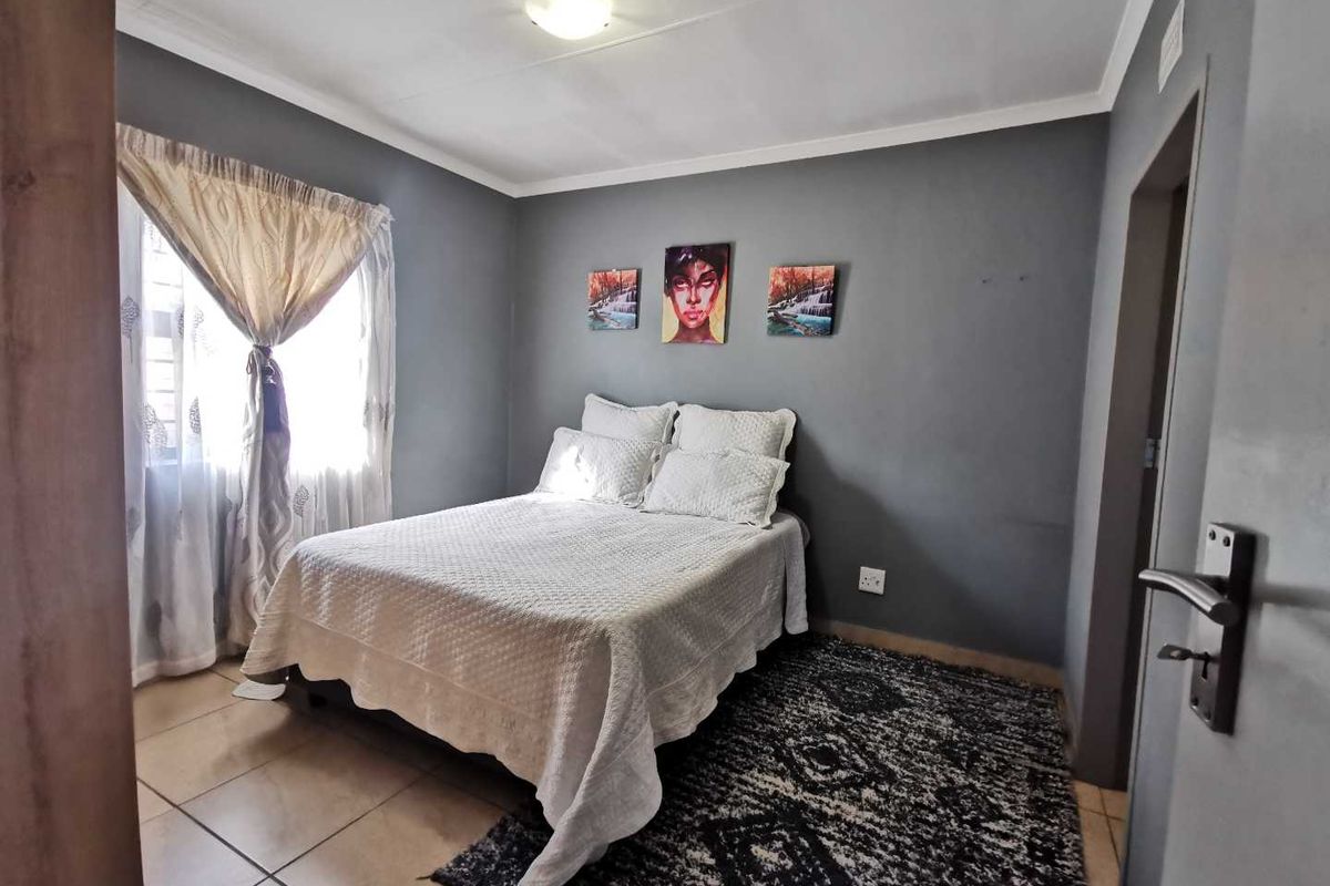 A well-maintained bedroom featuring neutral grey walls, tiled flooring, and a ceiling-mounted light fixture, offering a comfortable and functional living space.
