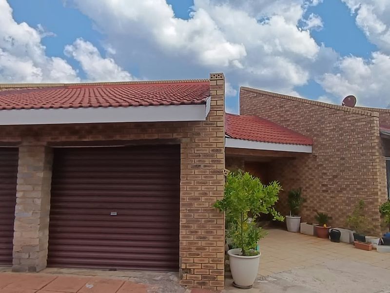 Front view of a face brick house featuring a double garage with roller doors and a covered entrance area.