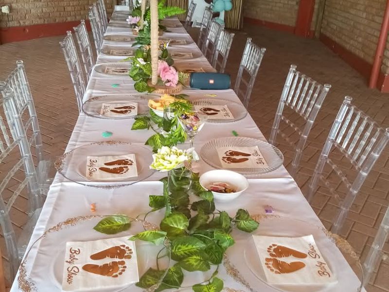 A covered outdoor patio area featuring exposed brick walls, a thatched roof, and paved flooring, suitable for hosting events and gatherings.