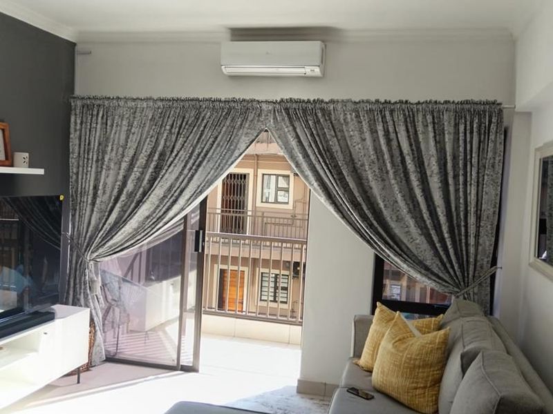A well-maintained living room featuring a split-system air conditioner, an accent wall, and a sliding glass door providing access to a balcony.