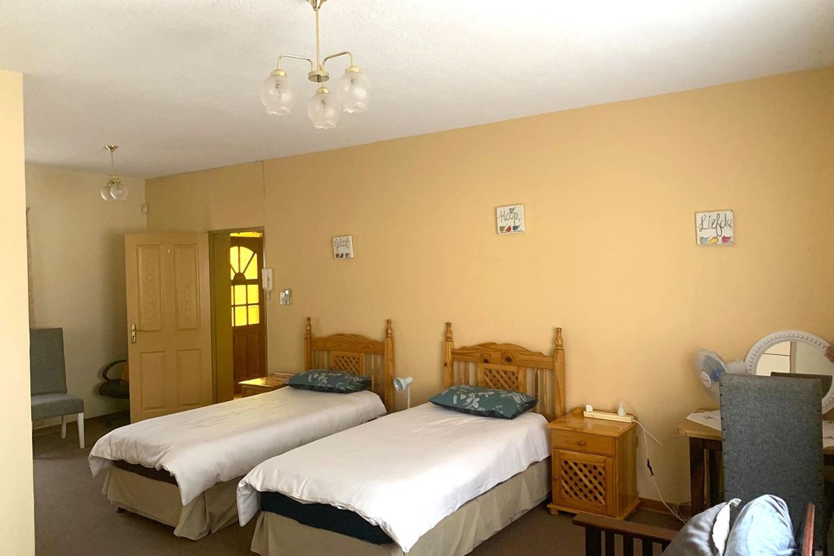 A spacious bedroom featuring neutral wall tones, carpeted flooring, and classic wooden door frames, offering a comfortable and functional living space.