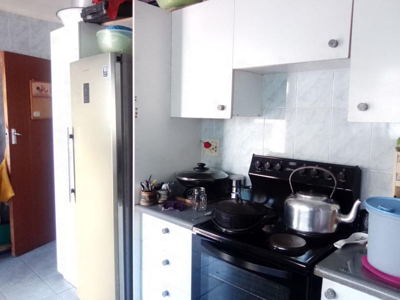 A functional kitchen featuring white built-in cabinetry, a tiled backsplash, and a freestanding electric stove with oven.