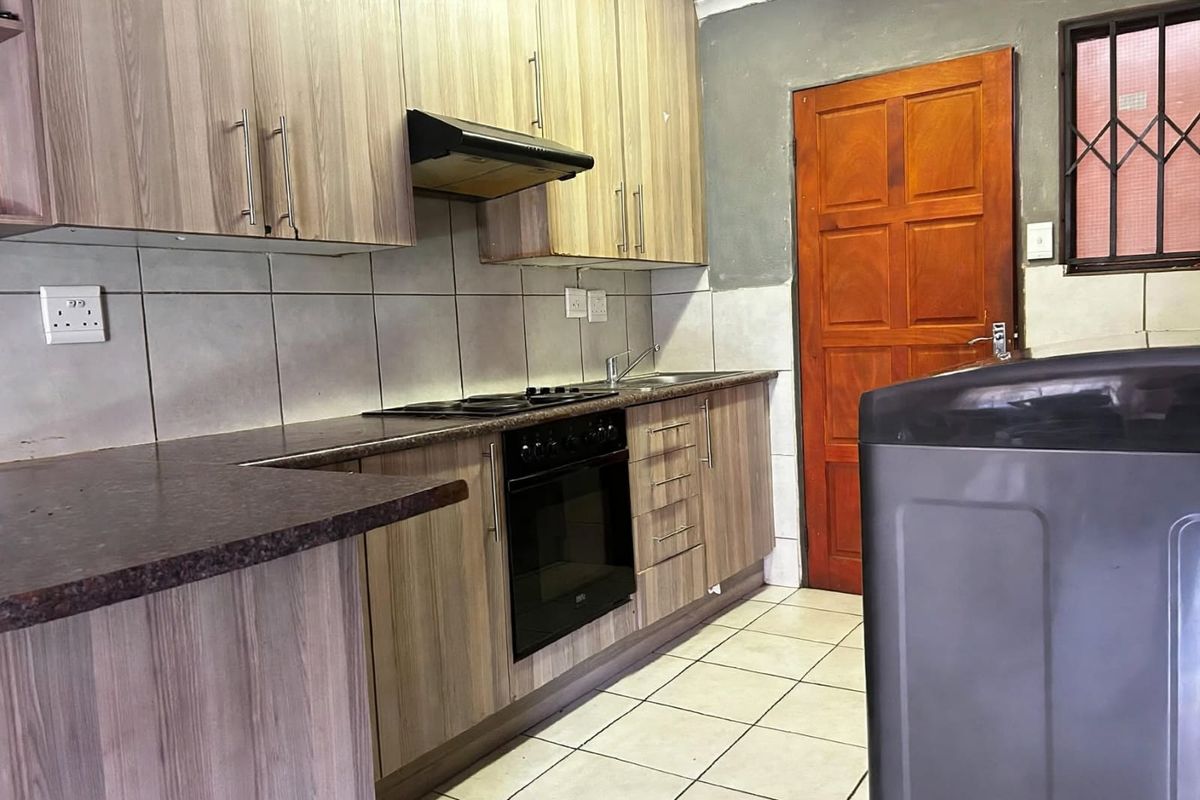 Functional kitchen featuring wood-look cabinetry, built-in oven and hob, tiled backsplash, and direct access to an exterior door.