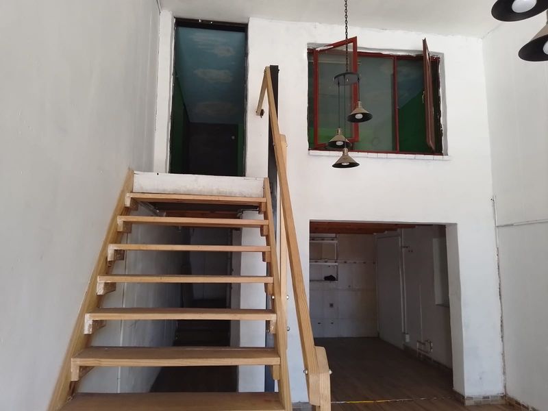 Open plan retail space featuring a wooden staircase, internal window, and high ceilings, offering a versatile layout for various business configurations.