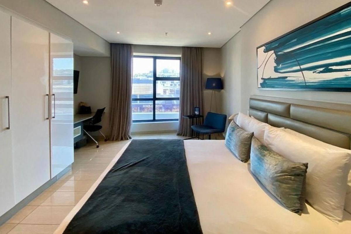 A well-maintained bedroom featuring built-in cupboards, tiled flooring, recessed lighting, and a large window with curtains.