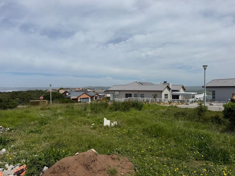 A view of a vacant residential plot in a developed estate, featuring surrounding homes, street lighting, and established infrastructure.