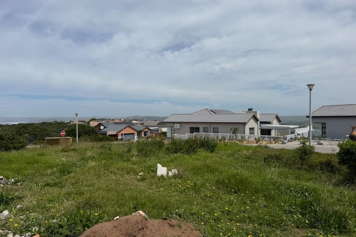 A view of a vacant residential plot in a developed estate, featuring surrounding homes, street lighting, and established infrastructure.