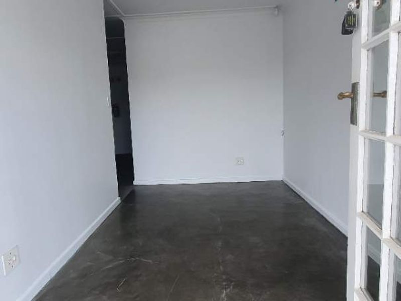 A bright, empty office space featuring polished concrete flooring, recessed lighting, and a classic French door entrance.