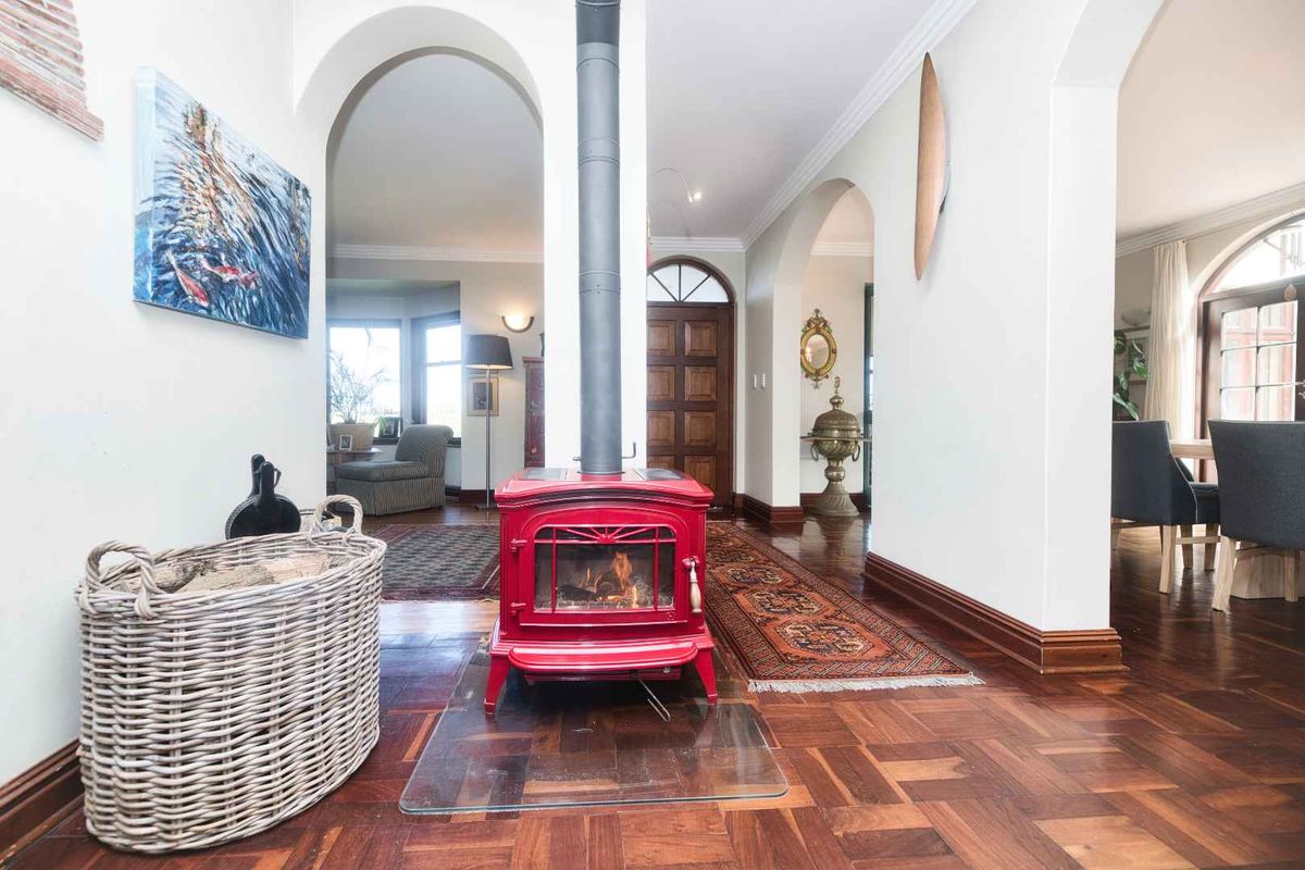 Spacious living area featuring rich parquet flooring, elegant arched doorways, and a prominent red freestanding wood-burning stove as a central focal point.
