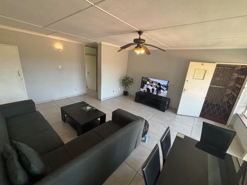 Open plan living and dining area featuring tiled flooring, a ceiling fan, and direct access to a secure entrance.