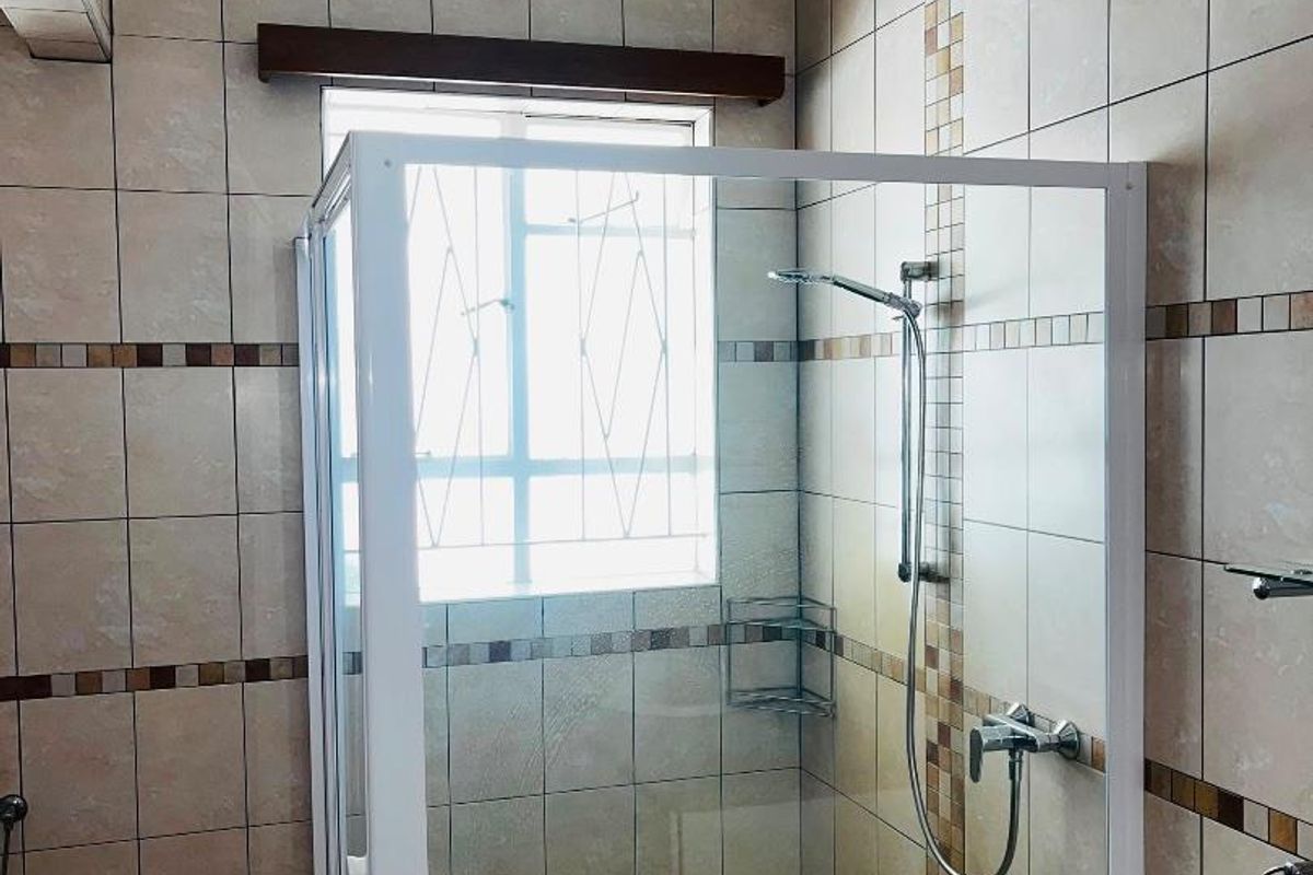 A functional bathroom featuring a glass-enclosed shower, tiled walls with decorative accents, and a vanity countertop.