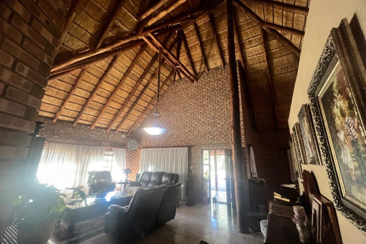 Spacious living room featuring a high vaulted thatched ceiling with exposed timber beams and rustic face-brick walls, creating a warm, traditional atmosphere.