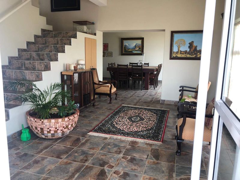 An open-plan living and dining area featuring slate tile flooring and a staircase with matching tiled risers and treads.