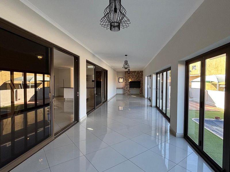 Spacious, light-filled living area featuring large sliding glass doors, polished tile flooring, and a modern stone feature wall, offering seamless indoor-outdoor flow.