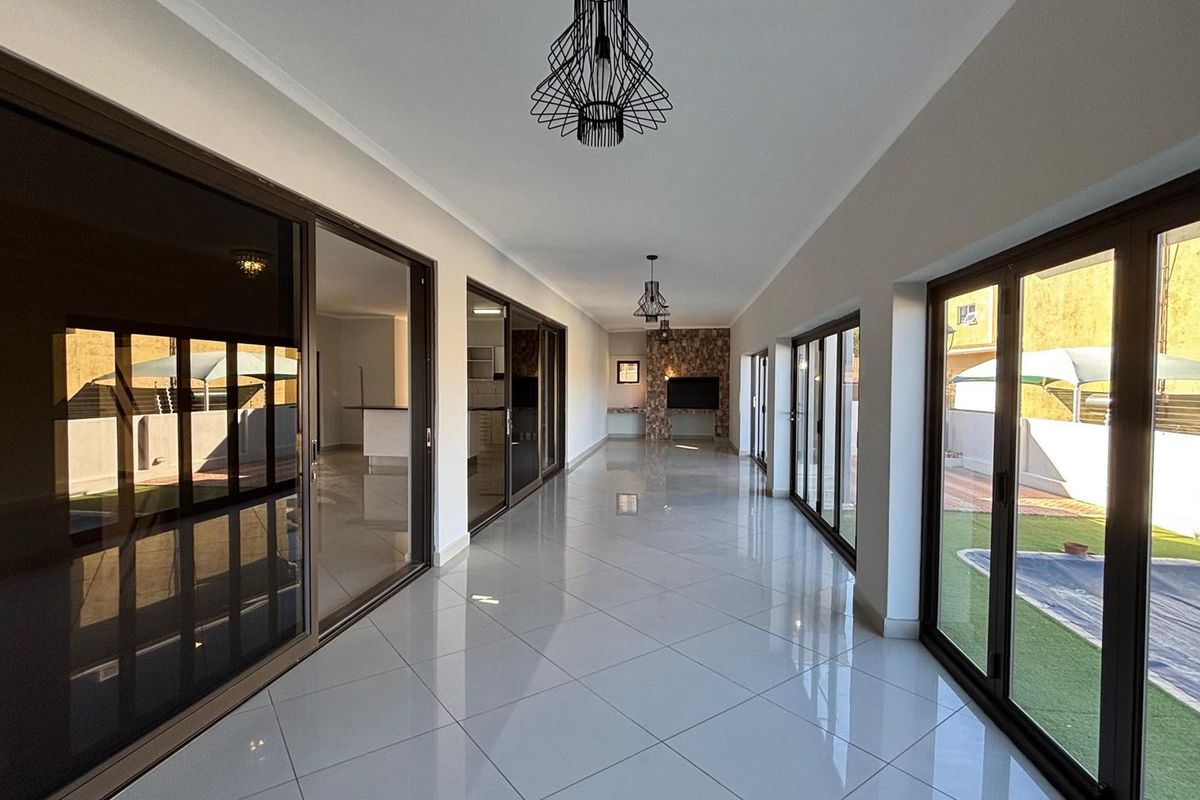 Spacious, light-filled living area featuring large sliding glass doors, polished tile flooring, and a modern stone feature wall, offering seamless indoor-outdoor flow.