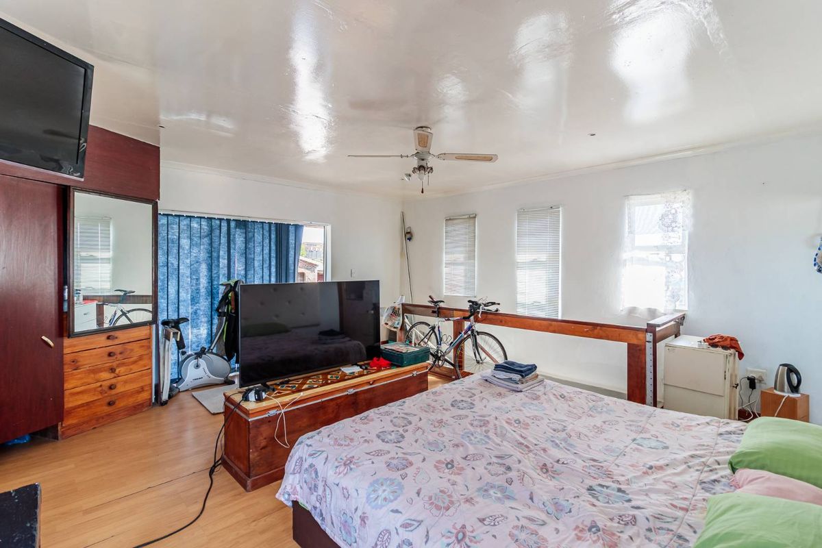 A spacious bedroom featuring laminate flooring, a ceiling fan, and multiple windows providing natural light.