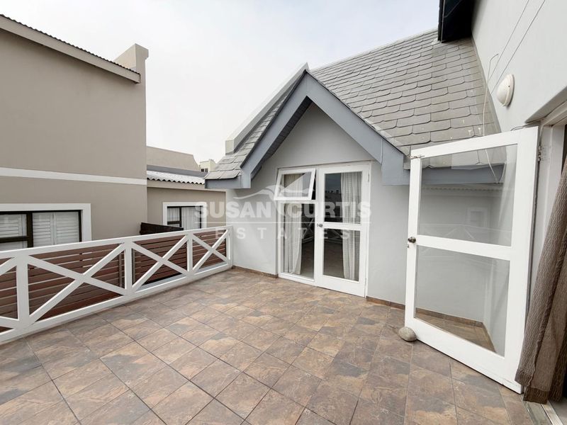 A private balcony featuring tiled flooring, a timber balustrade, and direct access through french doors to the upper level of the home.