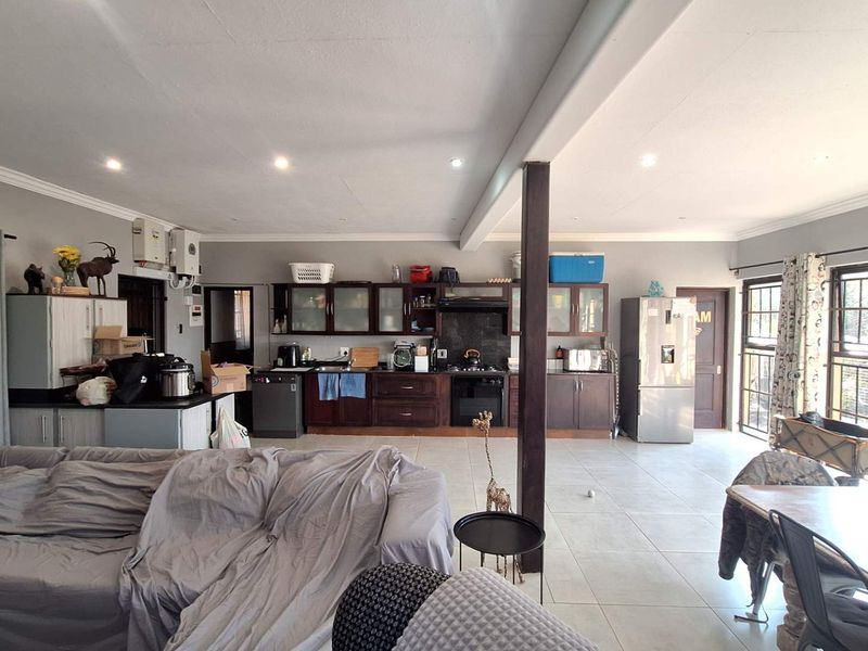 Spacious open-plan living and kitchen area featuring tiled flooring, built-in cabinetry, and a central support pillar, offering a functional layout for modern living.