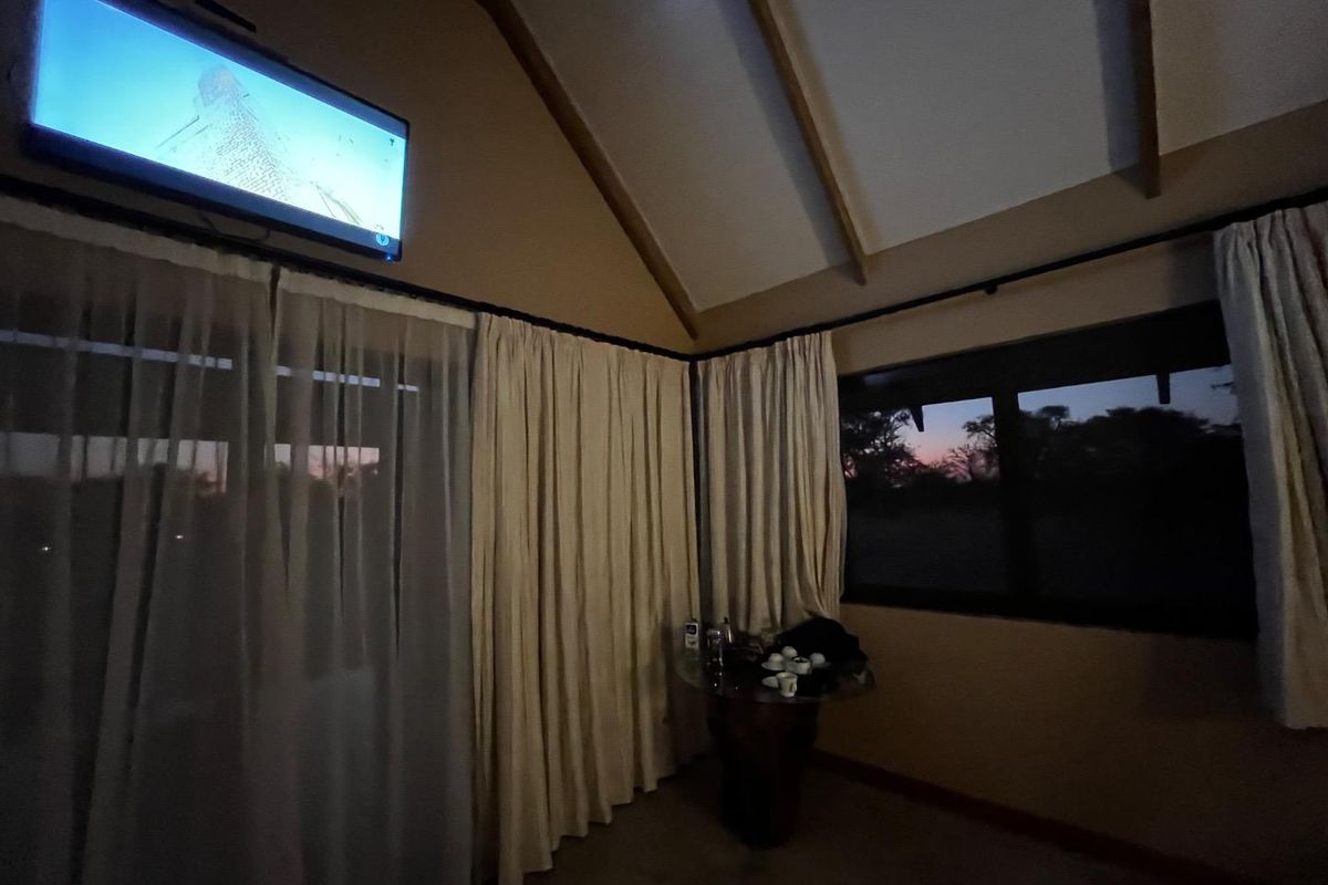 A bedroom featuring a high vaulted ceiling with exposed timber beams, large windows, and sliding glass doors providing natural light and outdoor views.